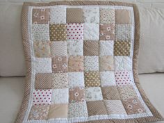 a close up of a quilt on a couch with pillows in the background and a white pillow behind it