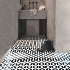 a bathroom with black and white flooring and a sink in the corner next to it