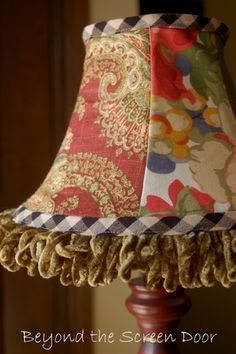 a lamp that is sitting on top of a wooden pole with a fabric shade over it