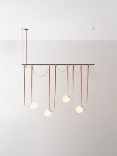 five lights hanging from the ceiling in a room with white walls and flooring,