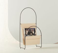 a magazine rack with two magazines in it on a white table next to a wall