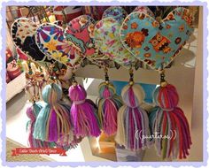 several heart shaped purses hanging from hooks in a store display case with tassels attached to them