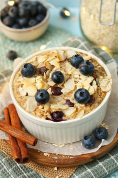 a bowl of oatmeal with blueberries and cinnamon sticks on the side