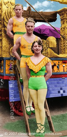 two men and a woman are posing for a photo in front of a carnival float