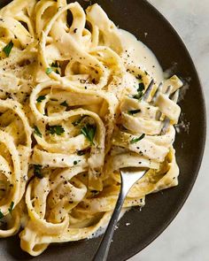 a plate full of pasta with sauce and parsley on the side next to a fork