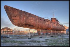 an old rusted boat sitting on top of a field