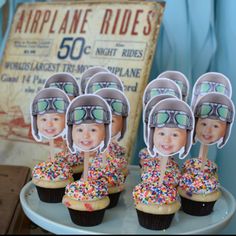 cupcakes with helmets and sprinkles are on a plate next to an old sign