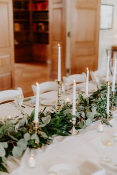 the table is set with candles and greenery