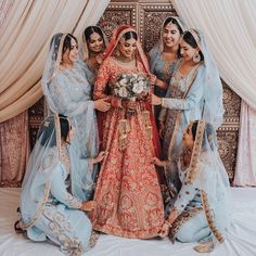 a group of women standing next to each other in front of a white wall with curtains