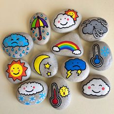 some rocks with different designs on them and one has an umbrella in the sky above it