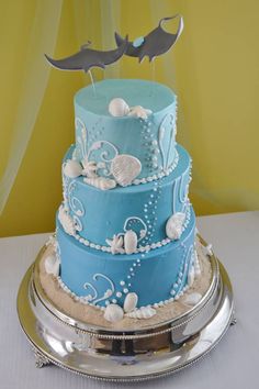 a three tiered cake with blue frosting and seashells