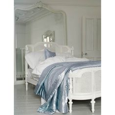 a white bed sitting in a bedroom next to a mirror