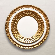 two plates with gold circles on them are sitting side by side in front of a white background