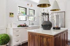 a kitchen with white walls and wooden floors, two pendant lights above the island counter