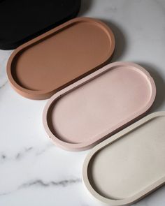 three oval trays sitting on top of a marble counter