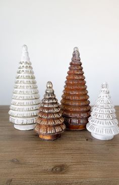 three ceramic christmas trees sitting on top of a wooden table