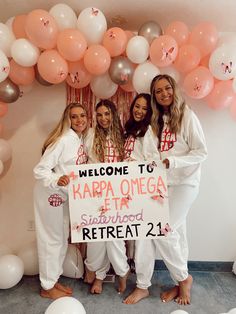 three women holding a sign in front of balloons with the words welcome to harra omega etta