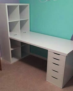 a white desk sitting next to a blue wall in a room with carpeted flooring