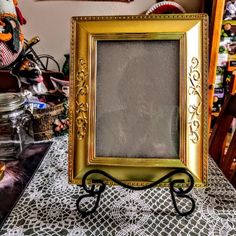 a gold frame sitting on top of a table next to a glass jar filled with stuff