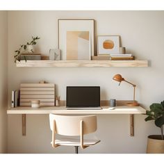 a laptop computer sitting on top of a wooden desk next to a potted plant