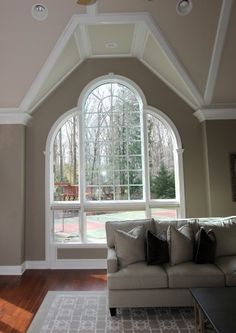 a living room filled with furniture and a large window covered in lots of white trim