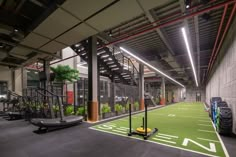 an indoor sports facility with artificial turf and treadmills on the floor, surrounded by plants