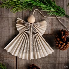 an ornament made out of folded paper with pine cones and evergreen branches around it