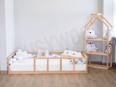 a baby crib with stuffed animals on it in a white room next to a wooden shelf