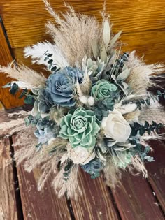 an arrangement of flowers and feathers on a wooden surface