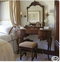 a bedroom with a dressing table, mirror and stool in it's corner next to a bed