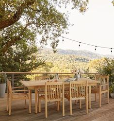 an outdoor dining table and chairs on a deck with string lights strung over the top