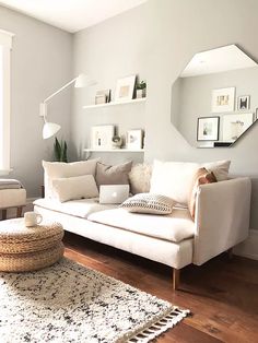 a living room with a white couch and pillows on the floor next to a mirror