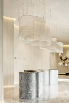 a marble counter in the middle of a room with chandelier hanging from the ceiling