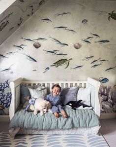 a boy laying in bed with his dog and fish mural on the wall behind him