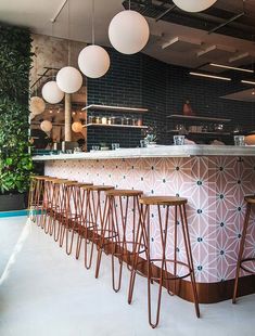 a bar with stools in front of it and hanging lights above the bar area