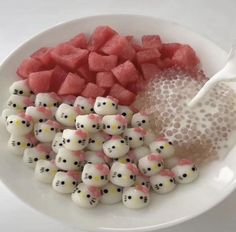 a white plate topped with lots of cut up watermelon and marshmallows