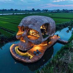 an unusual house in the middle of a rice field with a skull face on it's roof