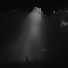 a person standing in the middle of a dark room with light coming from behind them