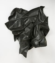 a piece of black leather on a white background with the fabric pulled back to reveal it's folds