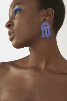 a close up of a person with blue eyeliners on their face and ear