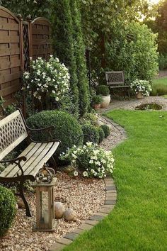 a wooden bench sitting in the middle of a lush green yard next to a fence