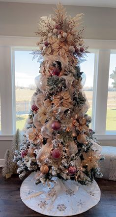 a decorated christmas tree with gold and red ornaments on it in front of a window