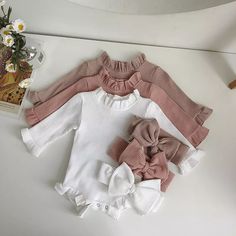 three baby onesuits with pink and white bows on the front, one is made from