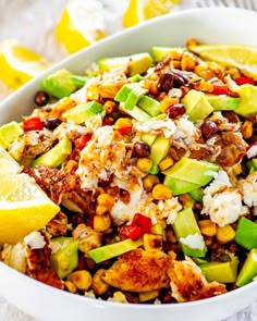 a white bowl filled with salad next to lemon wedges