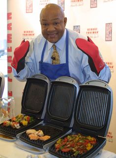 a man in an apron is holding up four grills with different foods on them