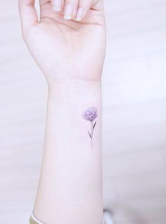 a woman's wrist tattoo with a single flower on the left side of her arm