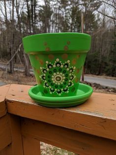 a green flower pot sitting on top of a wooden table