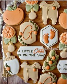 cookies decorated with baby's first names and oranges are arranged on a wooden board