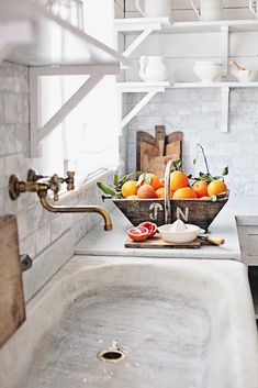 two bowls filled with fruit sitting on top of a kitchen counter next to a sink