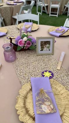 the table is set with purple and gold plates, napkins, and place settings